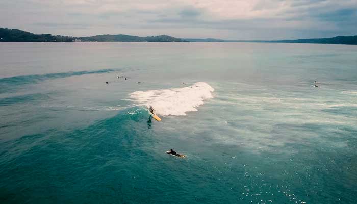 black rock surf spot in bocas del toro with surfer on a longboard and islands in the background