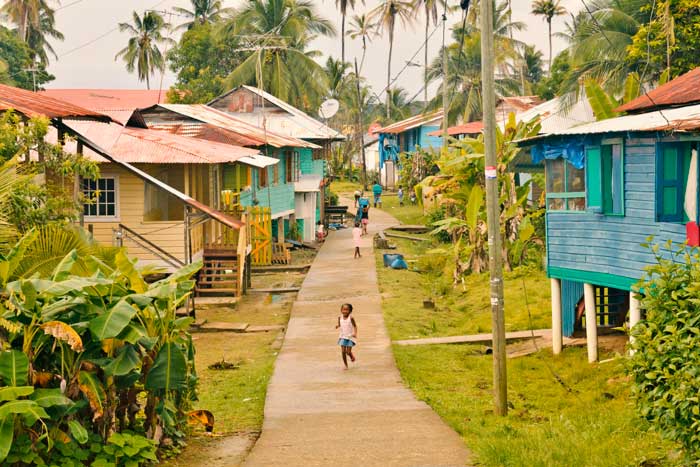 a girl runs down the sidewalk in the town of Old Bank on Isla Bastimentos