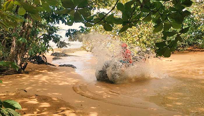A rider on a ATV spalshes through a river near Bluff Beach in Bocas del Toro, Panama.
