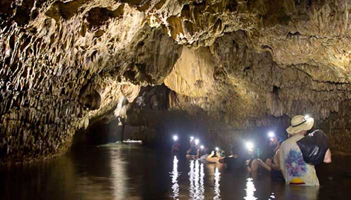 a group of tourists wades through waist high water inside the nivida bat cave on isla bastimentos in bocas del toro
