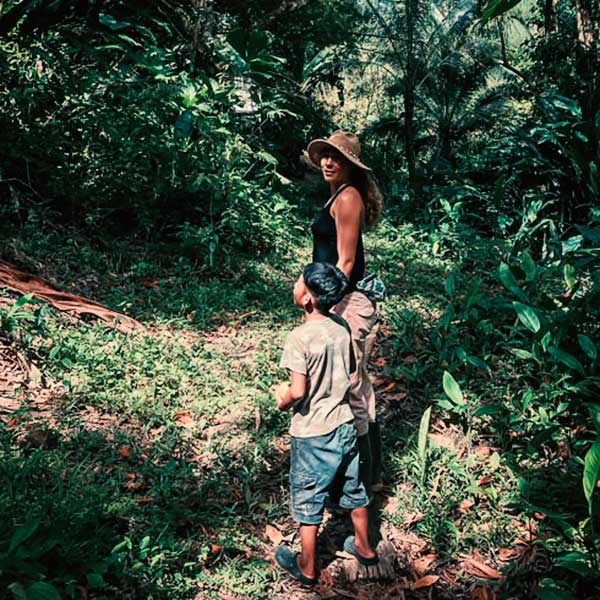 woman hiking through the jungle with local indigenous boy in bocas del toro on isla solarte