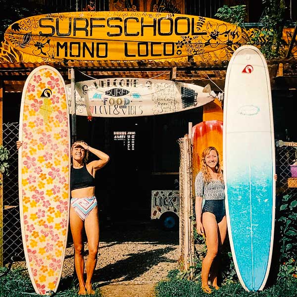 surfer girls with longboards in front of monoloco surf school in bocas town