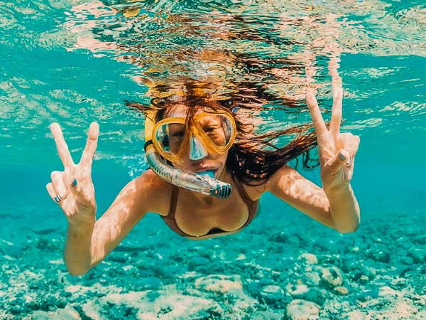 woman with peace sign hands snorkeling in bocas del toro panama