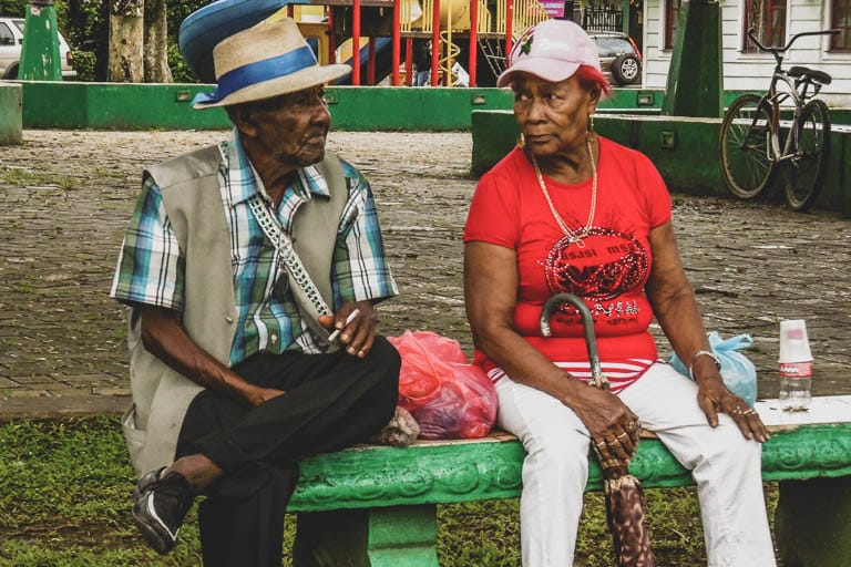 An elderly couple sit on a green bench at the central park in Bocas Town on Isla Colón in Bocas del Toro, Panama.