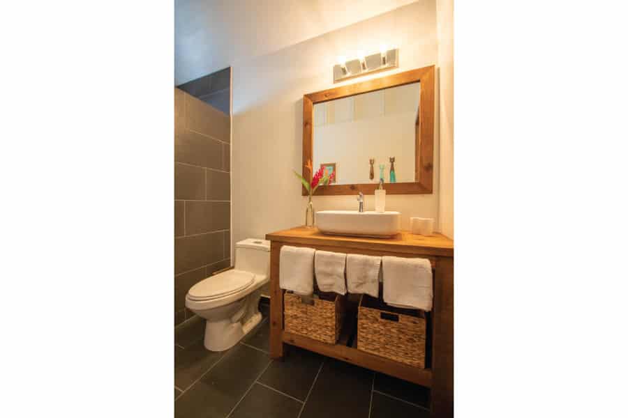 a bathroom with black tile and a mirror and toilet.