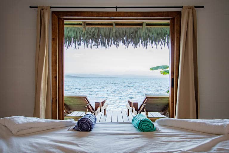 A view from the bed of Sol Bungalows with blue Caribbean water.