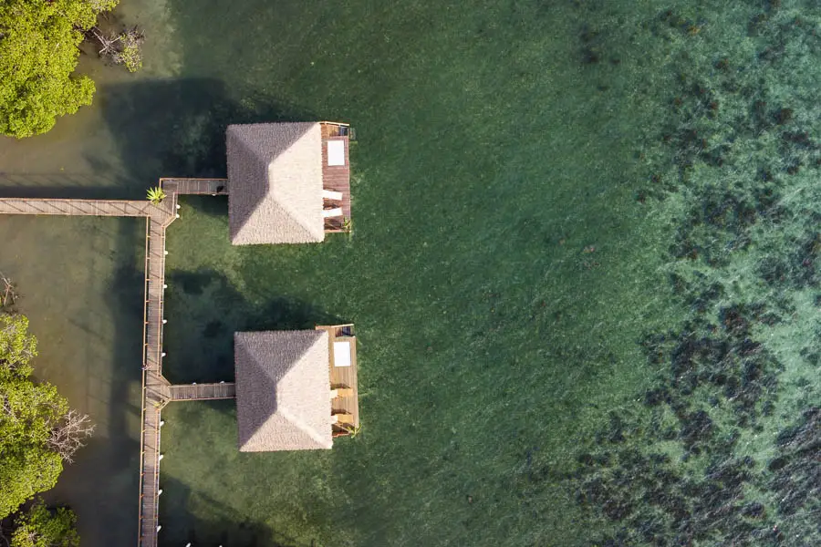 a drone of the two overwater bungalows with a reef for snorkeling in front.